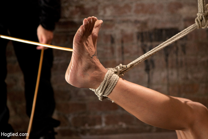 Sexy Amber has her elbows bound together, ankles to neck, and endures foot caning, brutal orgasms.